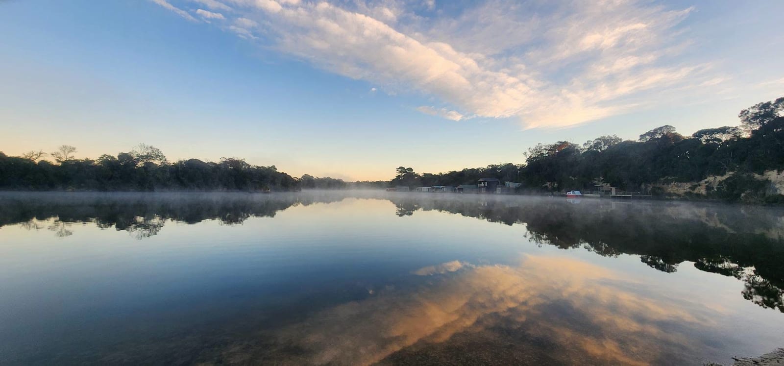 Morning mist lying on the Glenelg River with cloud reflected in the surface