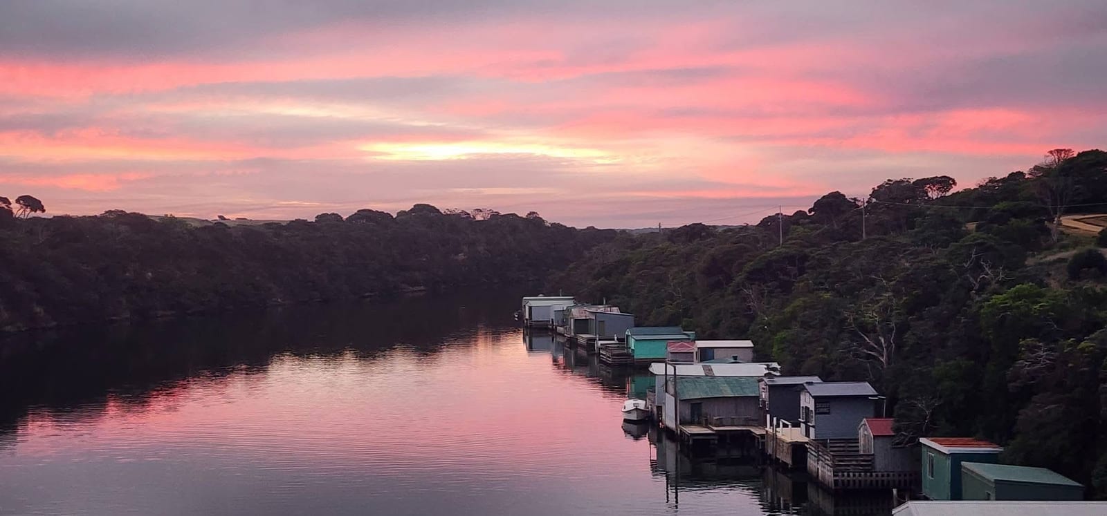 A pink sunset over the row of boat sheds along the Glenelg River